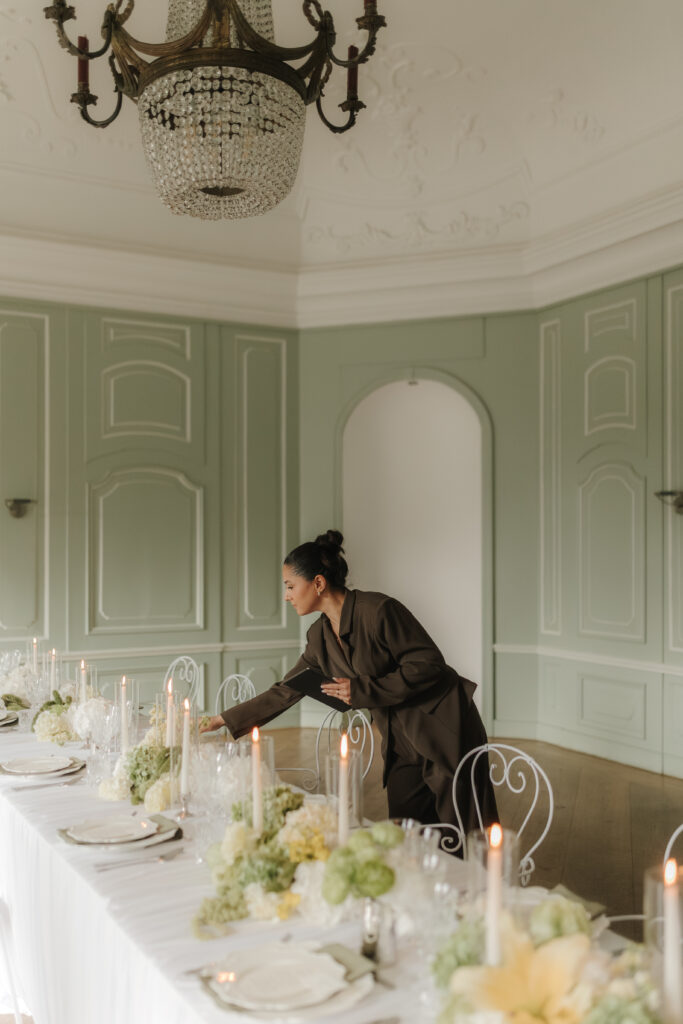Hochzeitsplanerin richtet Tischdekoration in exklusiver Hochzeitslocation im Rahmen der Komplettplanung aus