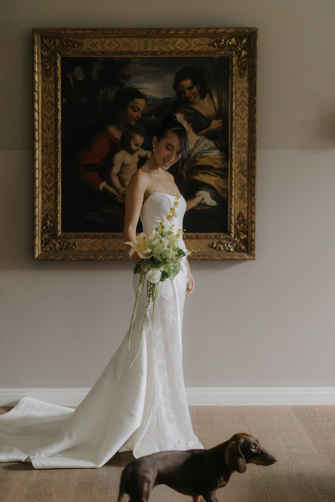 Bride in a modern wedding dress in a stylish villa with a bouquet and a dog
