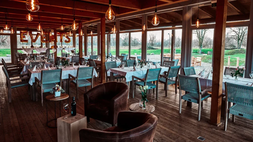 Elb Lodge Hamburg Hochzeitslocation Innenbereich mit Holzboden, warmem Licht und gedeckten Tischen für Hochzeitsfeier
