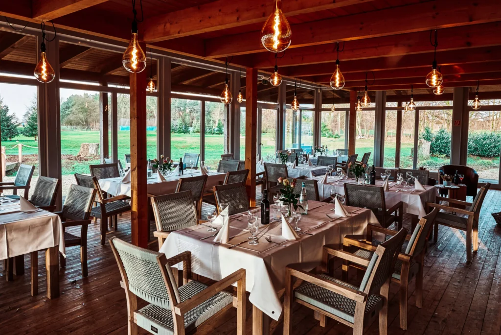 Hochzeit Elb Lodge Hamburg Innenraum mit gedeckten Tischen, Holzinterieur und Blick ins Grüne für stilvolles Dinner