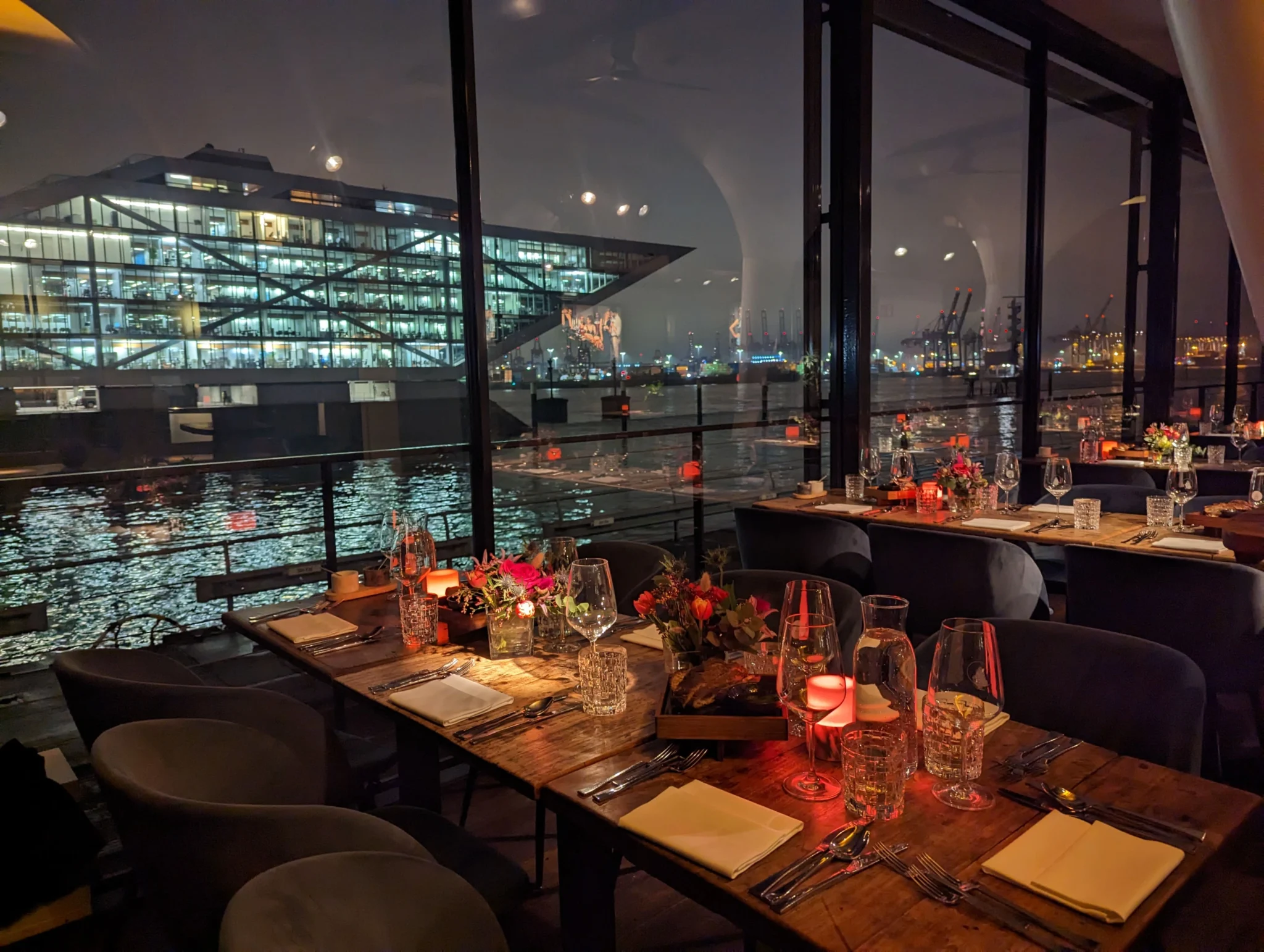 Abendliche Eventstimmung in der Eventlocation am Kai Hamburg mit gedeckten Tischen und Blick auf die beleuchtete Elbe