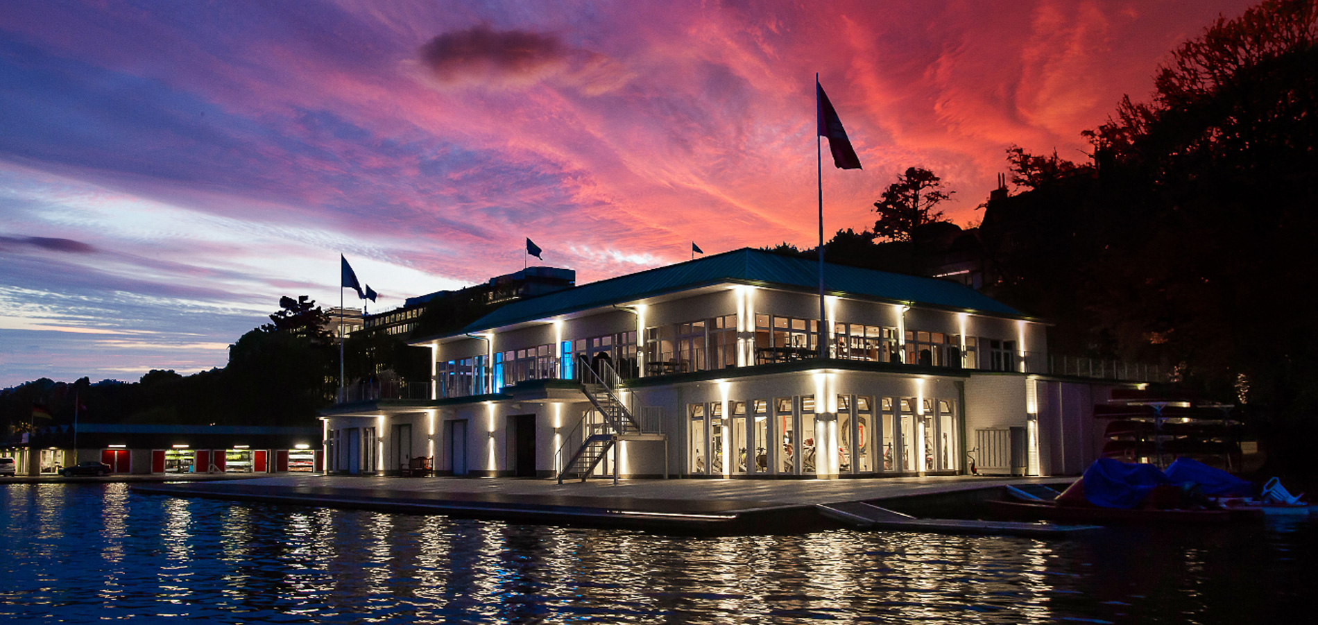 Außenansicht des Hamburger & Germania Ruder Clubs am Wasser in Hamburg bei Abendstimmung mit beleuchtetem Clubhaus