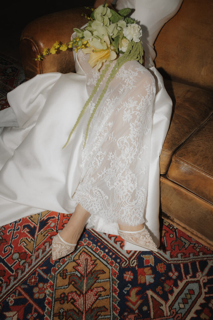 Detailaufnahme von Brautschuhen und Spitze des Kleides mit Blumenstrauß – Hochzeitsfotograf Hamburg