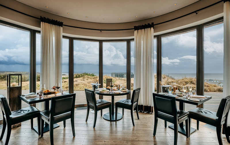 Innenarchitektur im Strönholt Sylt mit runder Fensterfront, modernem Restaurantdesign und Meerblick