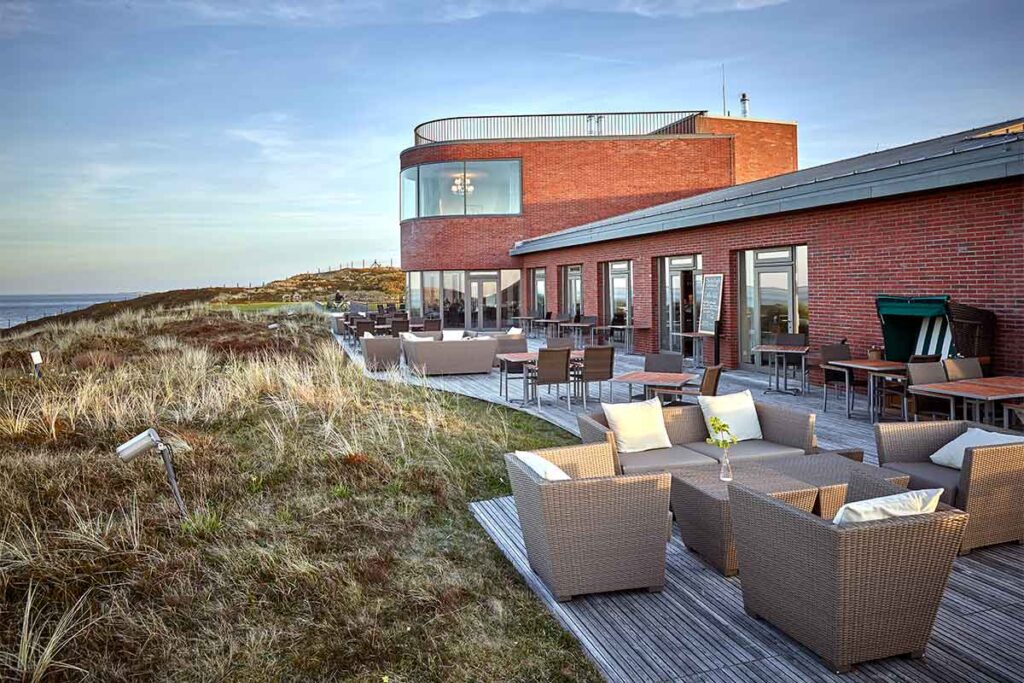 Terrasse des Strönholt Sylt mit Lounge-Möbeln, Blick auf die Dünenlandschaft und direkter Nähe zur Nordsee